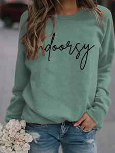 Close-up of Morandi green sweatshirt featuring black indoorsy script print and soft texture