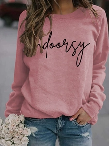 Detail of the Indoorsy print on a dusty rose crewneck sweatshirt paired with jeans