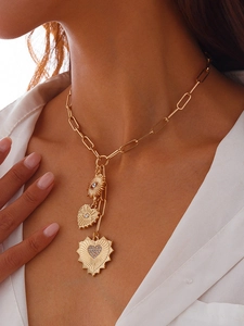 Close-up of golden triple-layered necklace with heart pendants and paperclip chain style