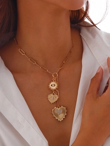 Detail of layered gold necklace featuring sunburst eye and shimmering heart pendants