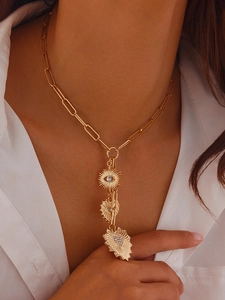 Detailed close-up of gold paperclip chain necklace with evil eye and heart charms
