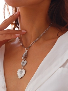 Close-up of triple heart pendants on silver paperclip chain worn with white shirt