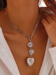 Macro view of silver paperclip chain with evil eye and layered heart charms