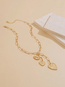 Macro detail of gold paperclip chain necklace with evil eye heart and sun pendants