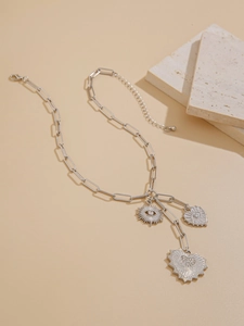 Detail of silver paperclip chain necklace with bohemian sun eye and heart charms