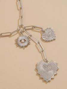 Detail of silver paperclip chain necklace with celestial sun eye and heart charms