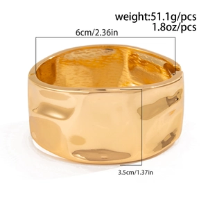 Macro shot showing dimensions and weight of the wide hammered gold metal bangle