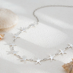 Silver starfish necklace set on a sandy beach background for a coastal ocean vibe