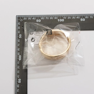 Polished gold alloy cuff bracelet with snap clasp shown against a ruler for sizing