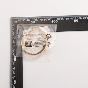Detail view of gold nail bracelet with polished finish next to a measuring ruler