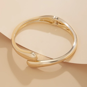 Detailed view of golden irregular teardrop bangle with polished finish and hinge closure