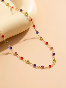 Detail of a gold-plated Y-necklace with multi-colored bezel-set round crystals