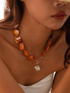 Bohemian orange shell bead necklace with gold toggle clasp and pearl drop on model
