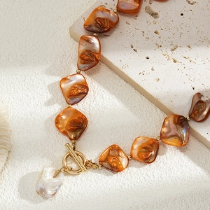 Detailed close-up of irregular shell beads and baroque pearl pendant on stone base