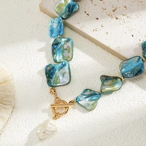 Detail of baroque pearl and iridescent shell beads with golden toggle clasp necklace