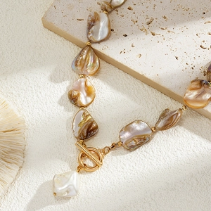 Macro detail of Baroque irregular pearls and shell necklace with gold OT toggle clasp
