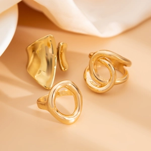 Detailed close-up of gold chunky ring set with irregular textures on soft silk fabric