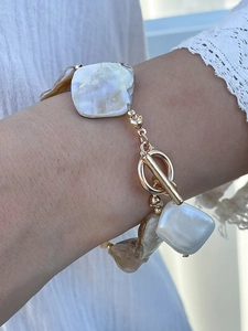 Detail of irregular freshwater pearl bracelet with golden toggle clasp on wrist