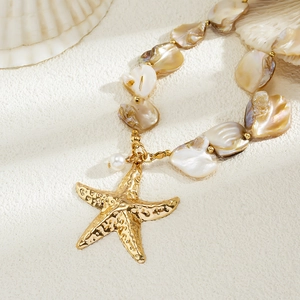 Detailed shot of bohemian shell beads with a large textured gold starfish pendant necklace