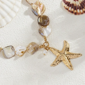 Close-up of bohemian beaded necklace with baroque pearls and golden starfish pendant