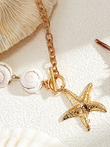 Detailed close-up of golden starfish pendant and shell bead with T-bar toggle clasp