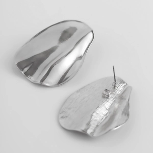 Vue détaillée de boucles d'oreilles irrégulières en argent aux finitions polies et brossées