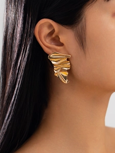 Macro view of gold irregular crinkle alloy earrings on model showing textured abstract design
