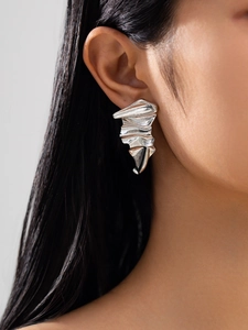 Close-up of silver irregular pleated earrings with high-shine liquid metal texture