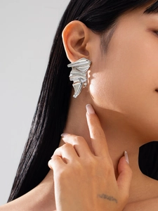 Close-up of silver irregular pleated earrings on model with reflective metallic texture