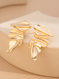 Macro shot of gold irregular wrinkled earrings with a modern abstract metal texture