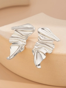 Detailed close-up of silver irregular pleated earrings on a textured stone display
