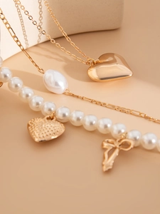 Detailed view of heart pendant necklace with baroque pearls and bow element