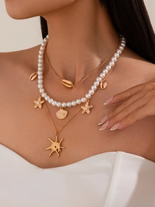 Detail of layered ocean-themed necklace with gold starfish shell charms and faux pearls