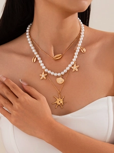 Detail of a layered ocean-style necklace featuring shell pendants and faux pearls