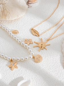 Detail of beach themed necklaces with pearls, gold starfish and seashell pendants