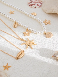Detailed shot of starfish and shell pendants on pearl necklace against sand texture