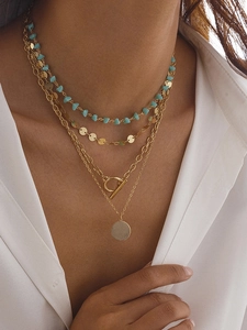 Gros plan d'un collier bohème multicouche avec perles turquoise et pendentif pièce d'or