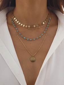 Gros plan d'un collier bohème doré à plusieurs rangs avec perles turquoise et pièces