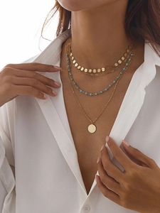 Collier multi-rangs avec pendentif pièce, perles bleues et sequins dorés sur un mannequin