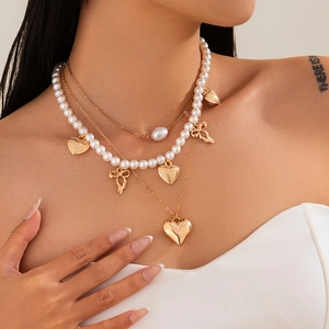 Layered gold necklace with heart and bow pendants featuring pearls for women beach style