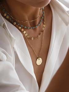 Détail d'un collier multicouche doré avec perles bleues et sequins sur mannequin