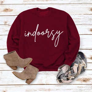 Flat lay of burgundy crewneck sweatshirt with white indoorsy print and autumn accessories
