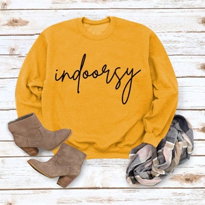 Flat lay of mustard yellow crewneck sweatshirt with indoorsy print and autumn boots