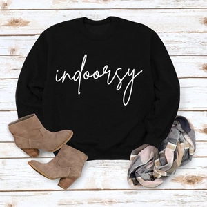 Flat lay of black crewneck sweatshirt with indoorsy print, boots and plaid scarf