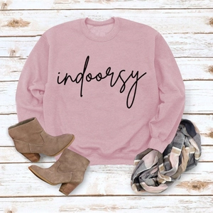 Flat lay of a light pink crewneck sweatshirt with indoorsy print and ribbed cuffs