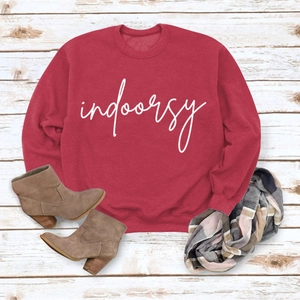Flat lay of red crewneck sweatshirt with indoorsy print and plaid scarf on wood