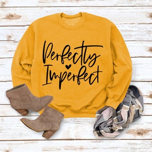 Flat lay of ginger sweatshirt with Perfectly Imperfect print on wood background