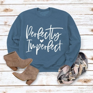 Flat lay of blue sweatshirt with 'Perfectly Imperfect' print, scarf and brown boots