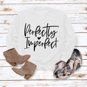 Flat lay of Perfectly Imperfect white sweatshirt with a heart print on rustic wood