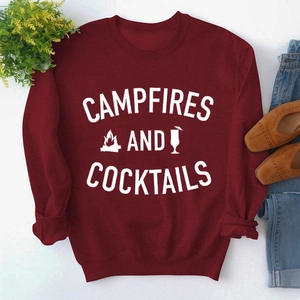 Close-up of Campfires and Cocktails graphic on a burgundy crewneck sweatshirt with styling items